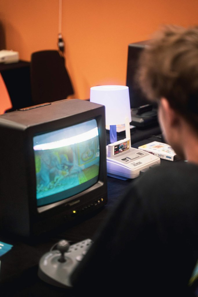 Jugendlicher schaut auf einen alten CRT-Röhrenfernseher mit laufendem Retro-Game, daneben ein Super Nintendo Mini